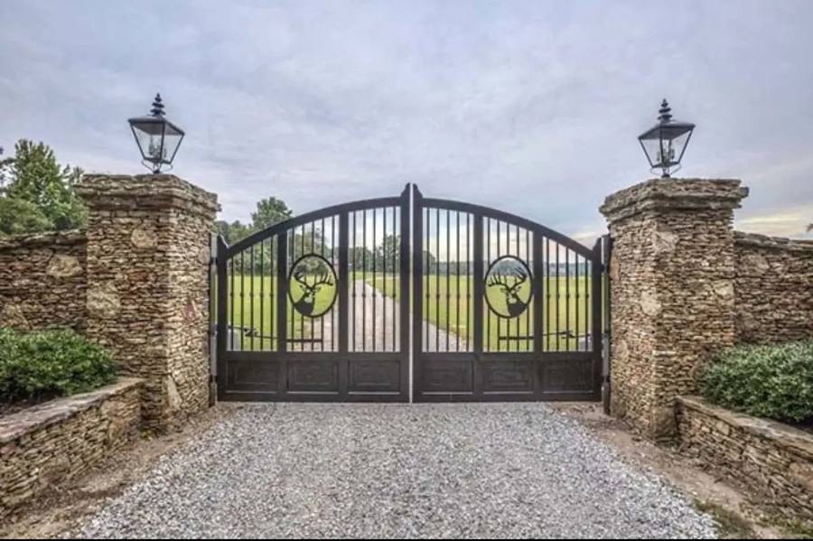 Custom estate driveway gate with deer medallions and stone pillars