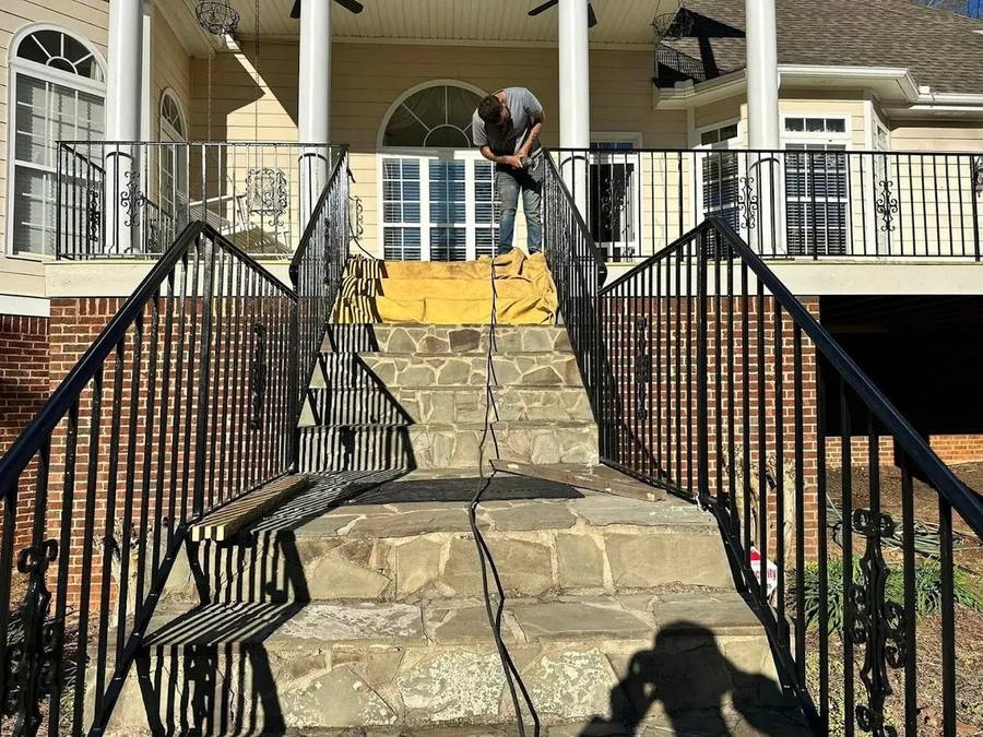 Custom iron stair railing installation on stone steps